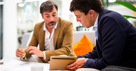 Two business professionals reviewing investment documents together in a modern office